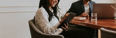 Two people sitting in conference room, one of them writing on tablet, Support Services | DXC Technology Insights